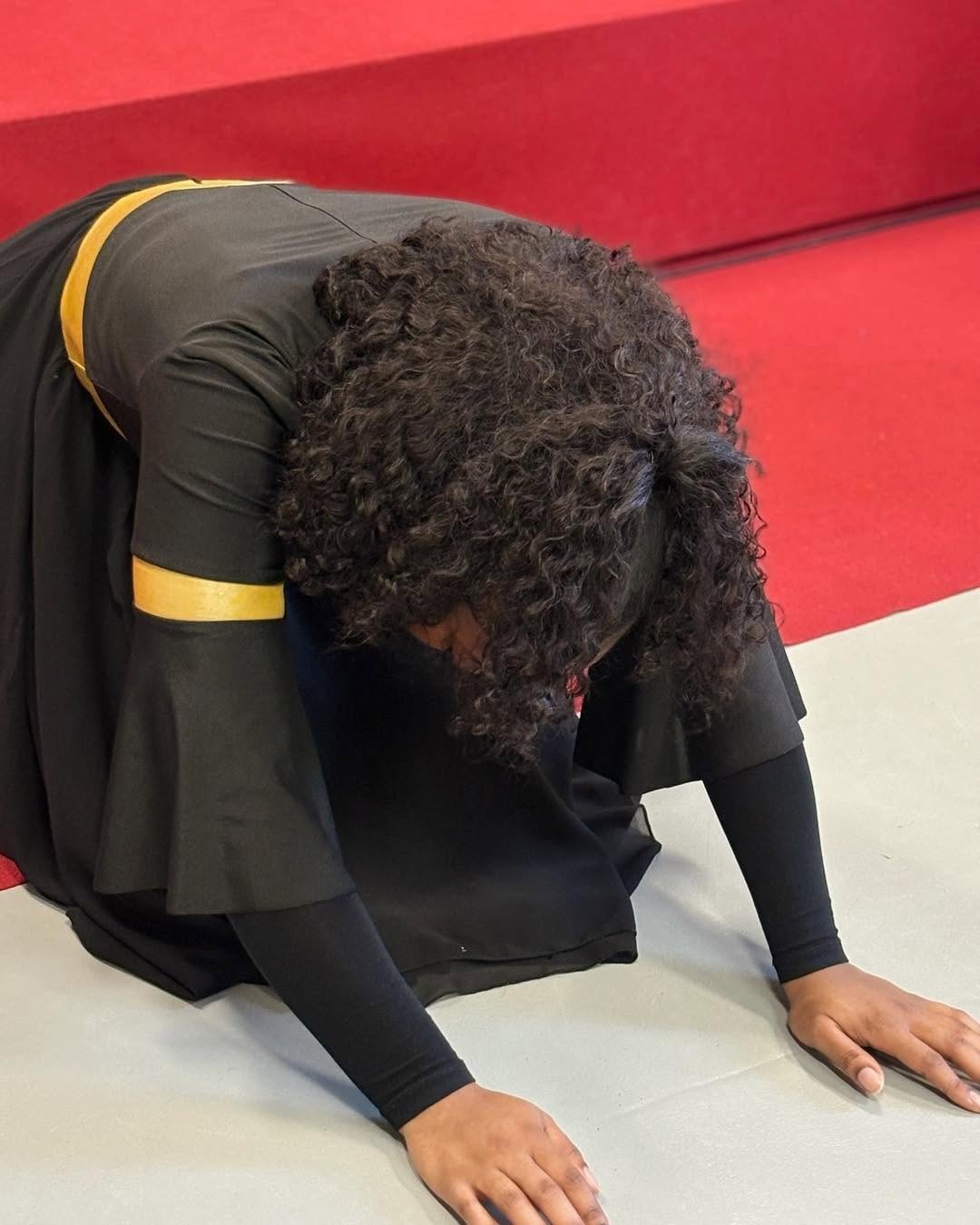 Een vrouw buigt zich neer in gebed op de vloer van de kerk